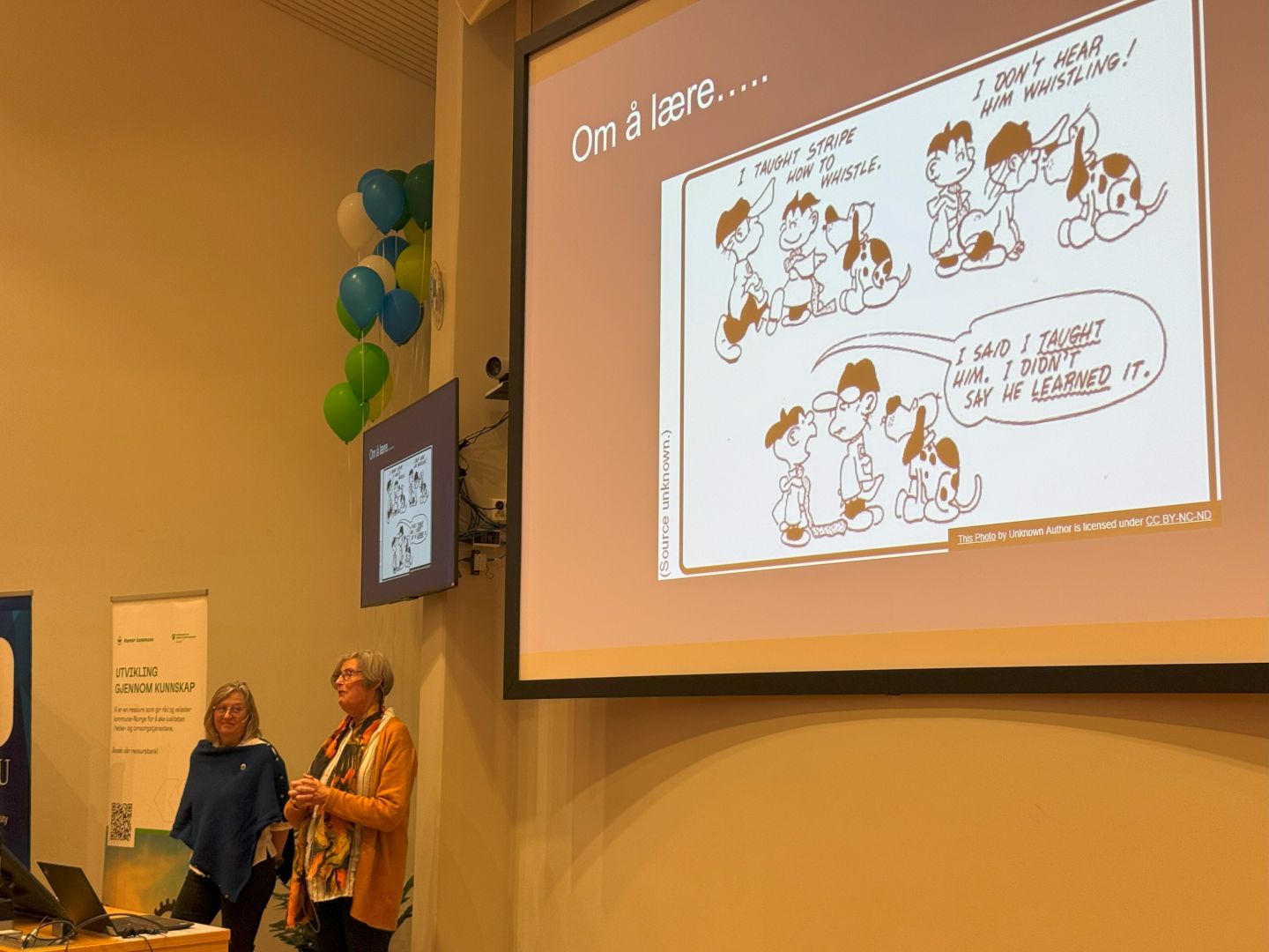 To kvinner holder foredrag med en storskjerm i bakgrunnen med en tegneseriestripe som illustrerer  at man ikke nødvendigvis har lært noe fordi noen har prøvd å lære en det