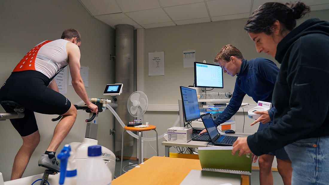 To studenter som ser på en mann som gjennomfører en sykkeltest. 