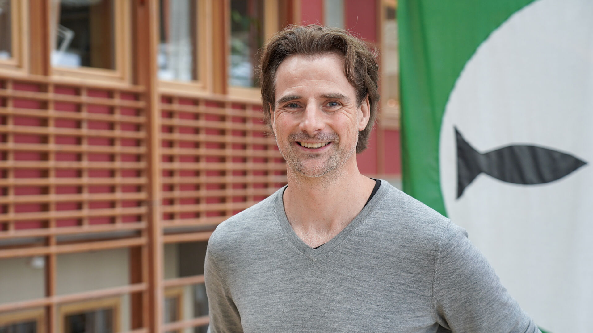 Mann står foran store flagg med symboler på