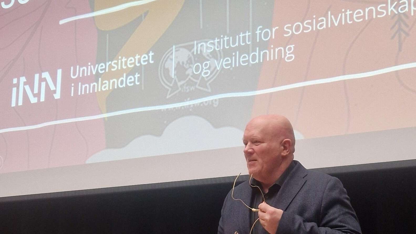 Rektor holder presentasjon med en stor skjerm i bakgrunnen
