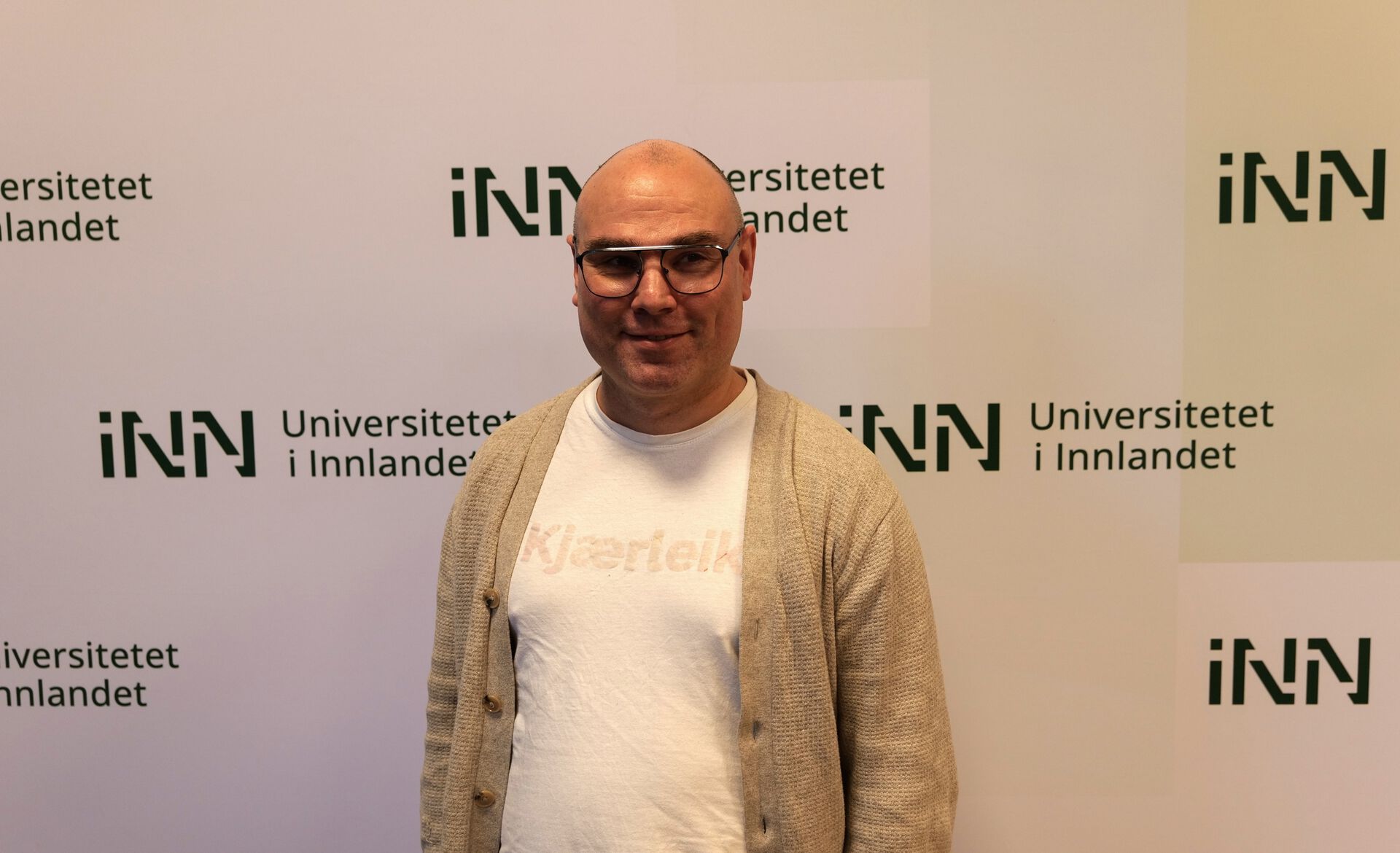 Gjølme står foran en vegg med INN-logoer