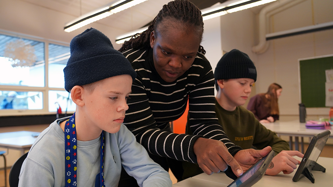 Lærerstudent som underviser to unge gutter i et klassrom. 