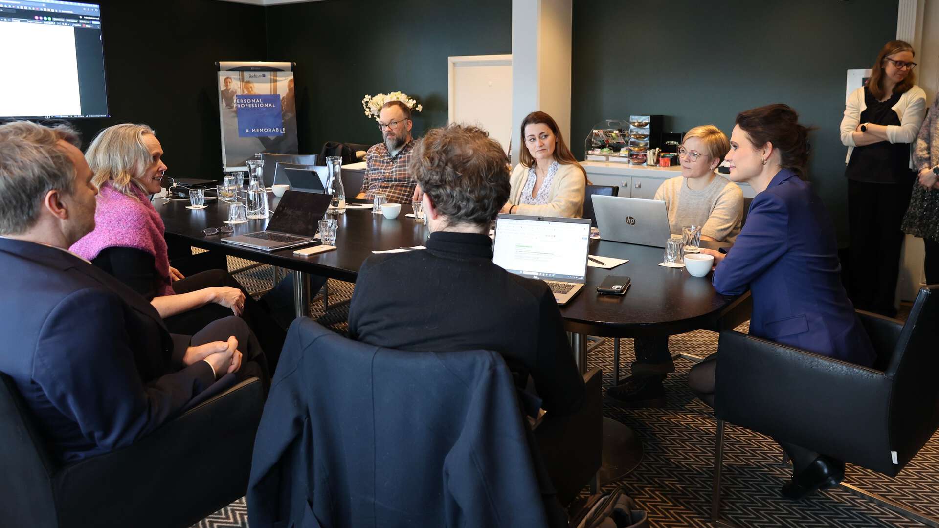 En gruppe mennesker sitter rundt et bord og diskuterer