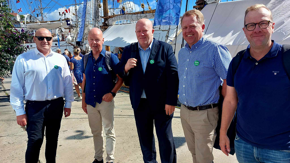 Gruppebilde av fem menn i pene, mørke klær på Arendalsuka. 