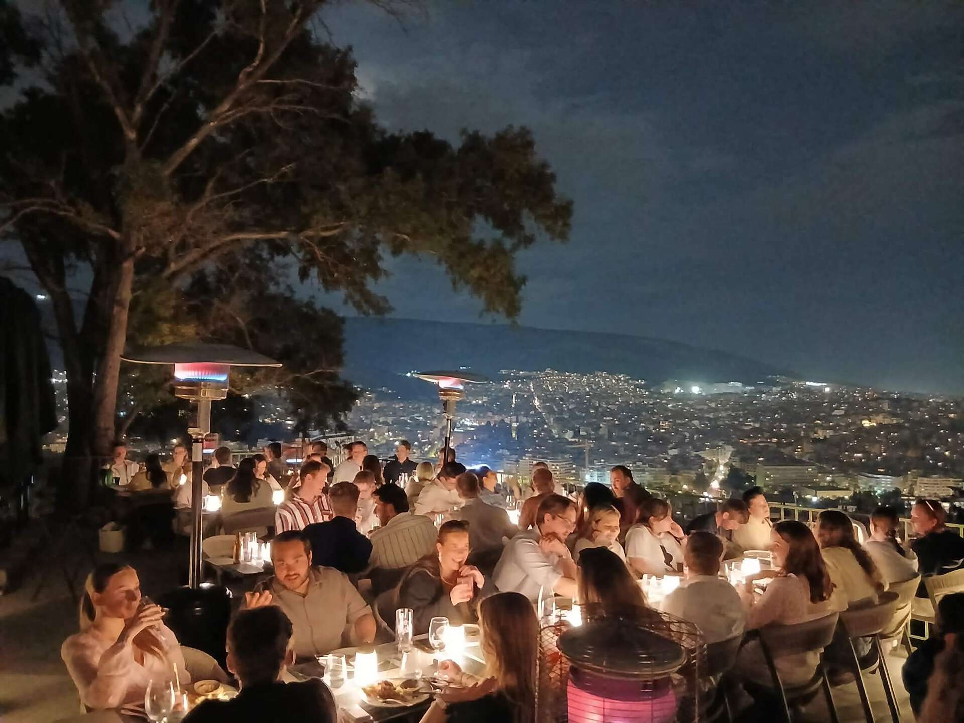 Bilde av alle i reisefølget siste kvelden på en uterestaurant med utsikt over Athen fra Lycabettus-høyden.