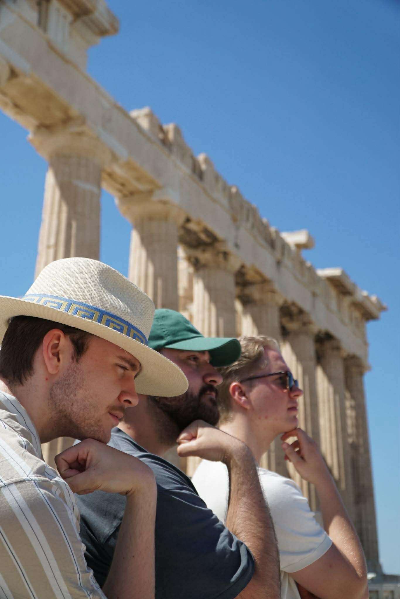 Bilde av studentene som sitter og grubler ved Parthenon-templet på Akropolis, fra v. Mathias Høston, Mohammed Bayazidi og Jens Grepstad.