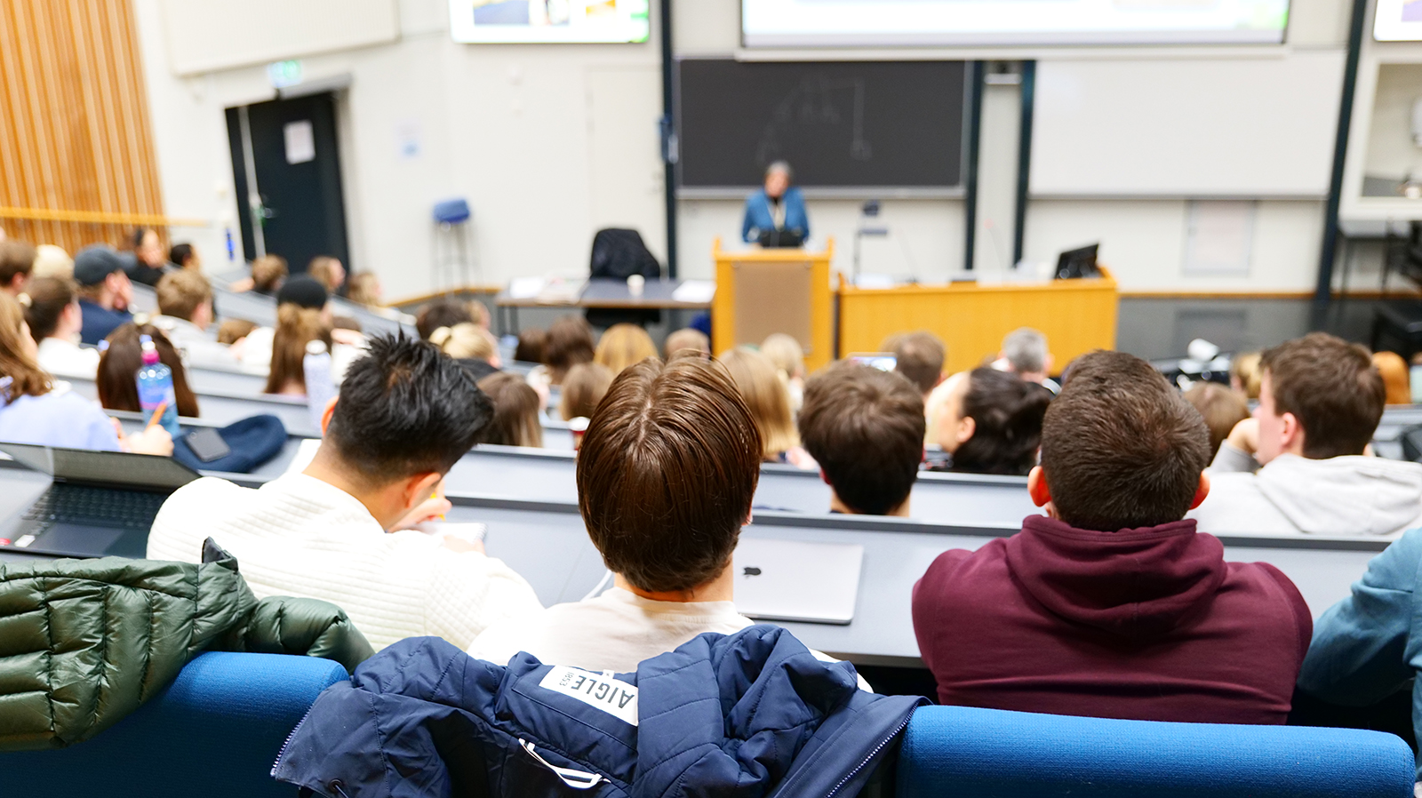 Bilde av bakhodet til studenter som sitter i auditorium 1 på studiested Hamar og følger med på undervisning.