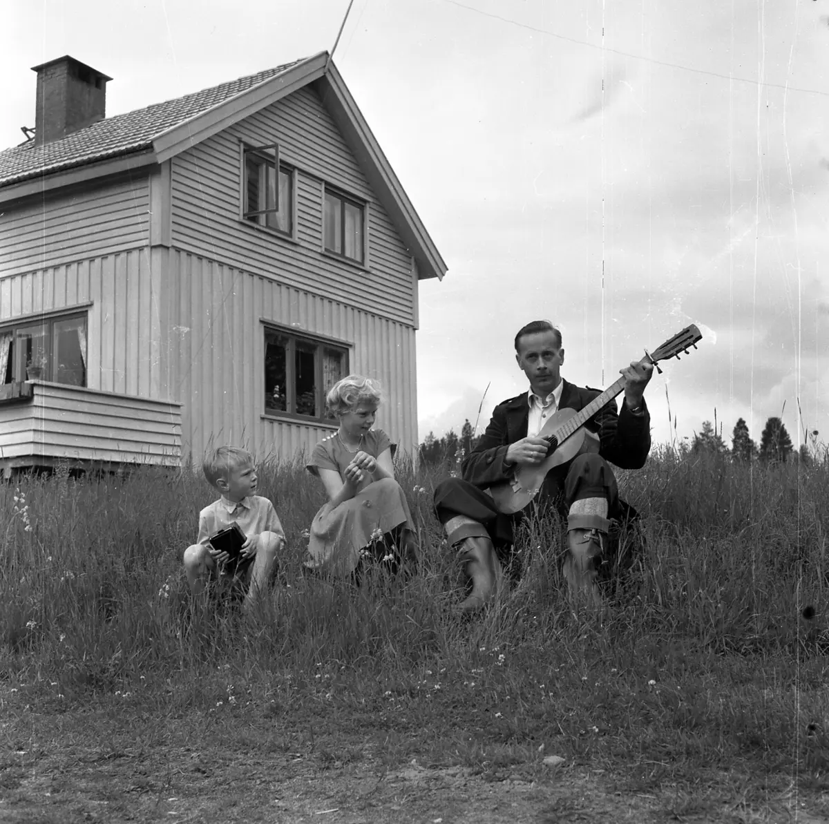 Vidar Sandbeck med familie musiserer foran hus