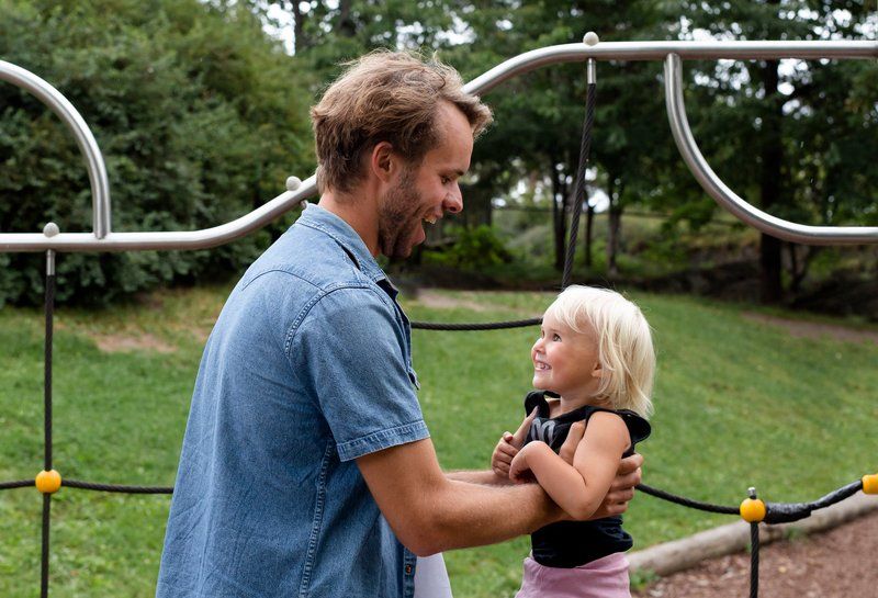 Man holds child in arms at playground