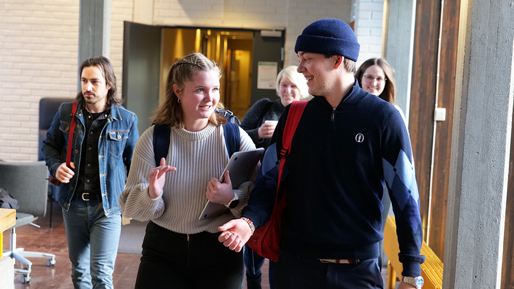 Fem studenter som går og diskuterer i gangen på studiested Hamar.