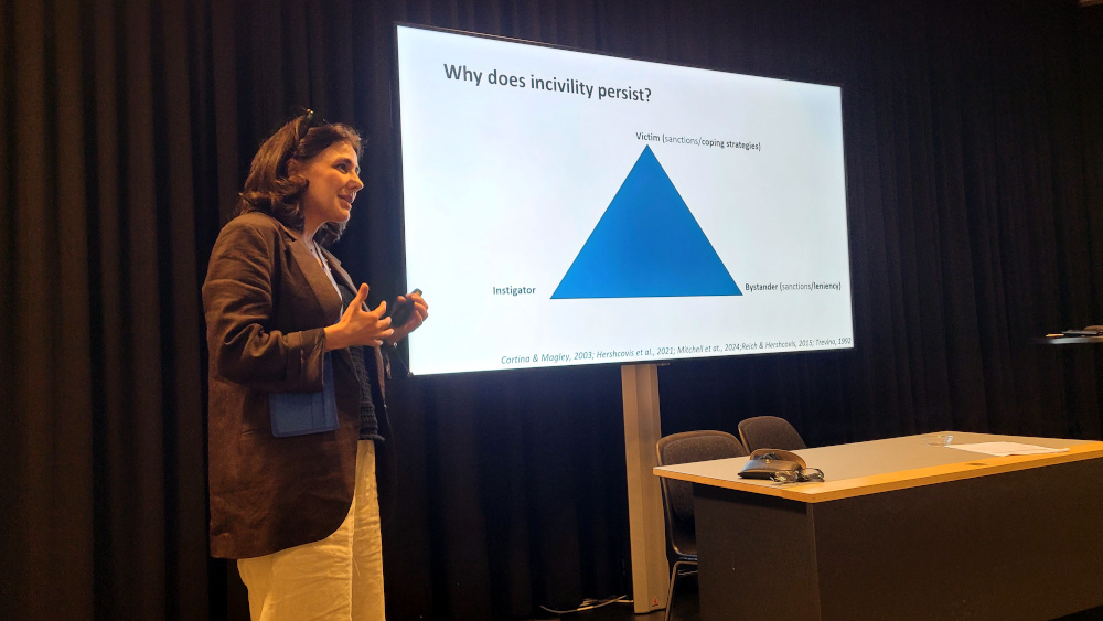 Afra Koulaei står ved siden av en skjerm med en powerpointpresentasjon