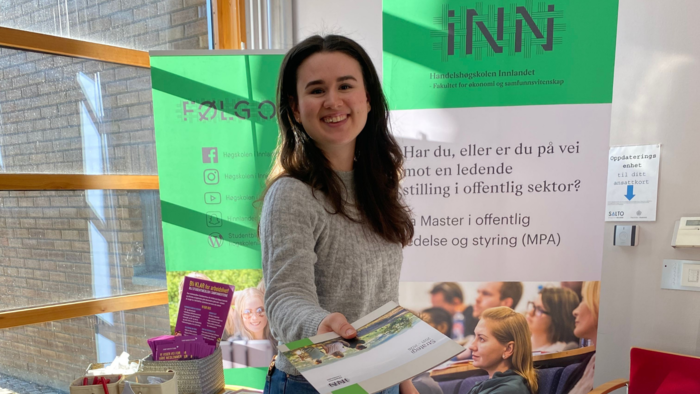 Smilende studieveileder ved HHS som deler ut flyers ved stand