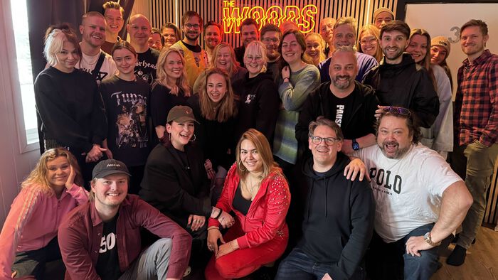 Cirka 30 persons are lined up for a group photo in a studio. everyone is smiling.