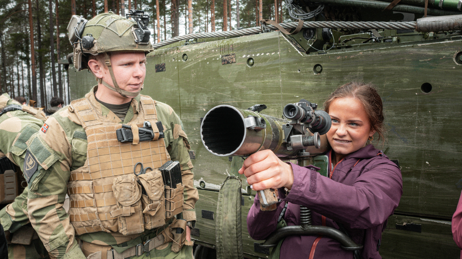 Jente holder en m72 på skulderen sin og står ved siden av en soldat