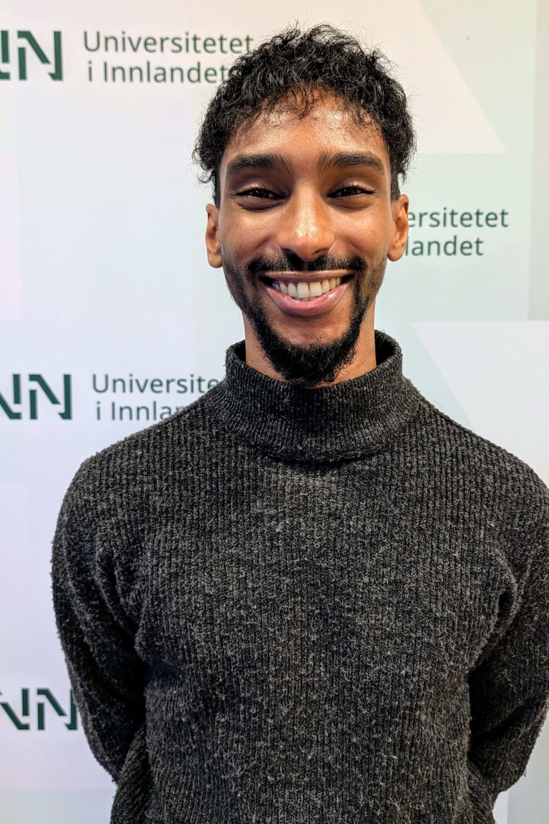 Student Khaled Abdelrahim foran en bakgrunn med INNs logo