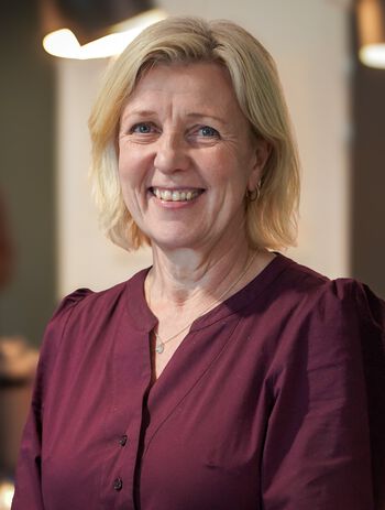 Dame med lilla topp mot en uskarp bakgrunn inne i et rom