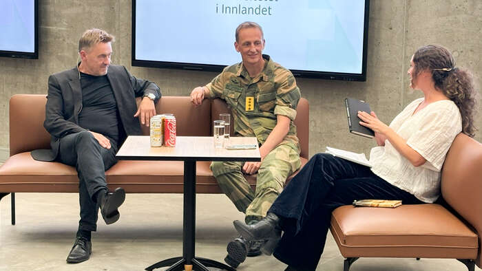 Panelet på en av podkastene i en sofa på scenen 