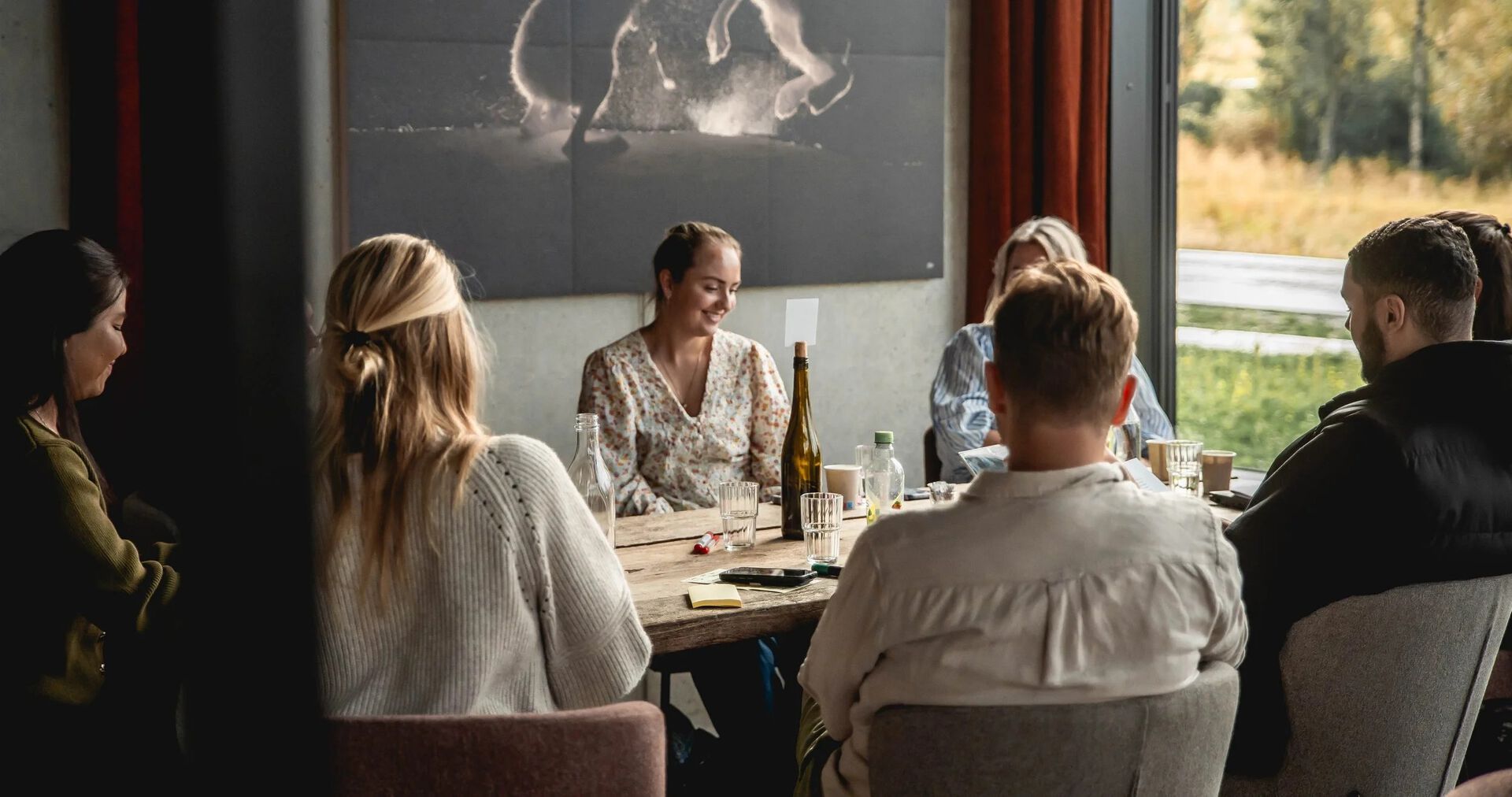 Unge studenter sitter rundt et bord med stort vindu i bakgrunnen