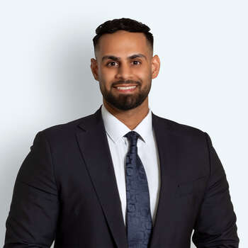 Portrett av Haroon Malik i mørk dress foran en lys bakgrunn.