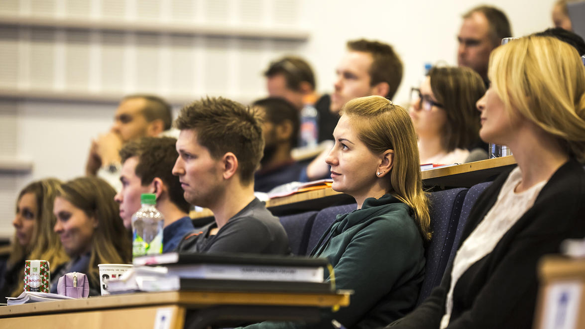 En samling studenter som følger undervisning i auditorium. 