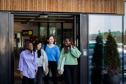 Fire smilende jenter på vei ut av hoveddøra på studiested Elverum.