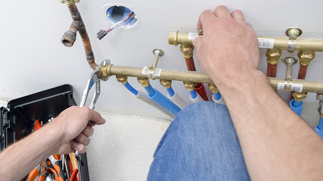 Two hands placed on water pipes.