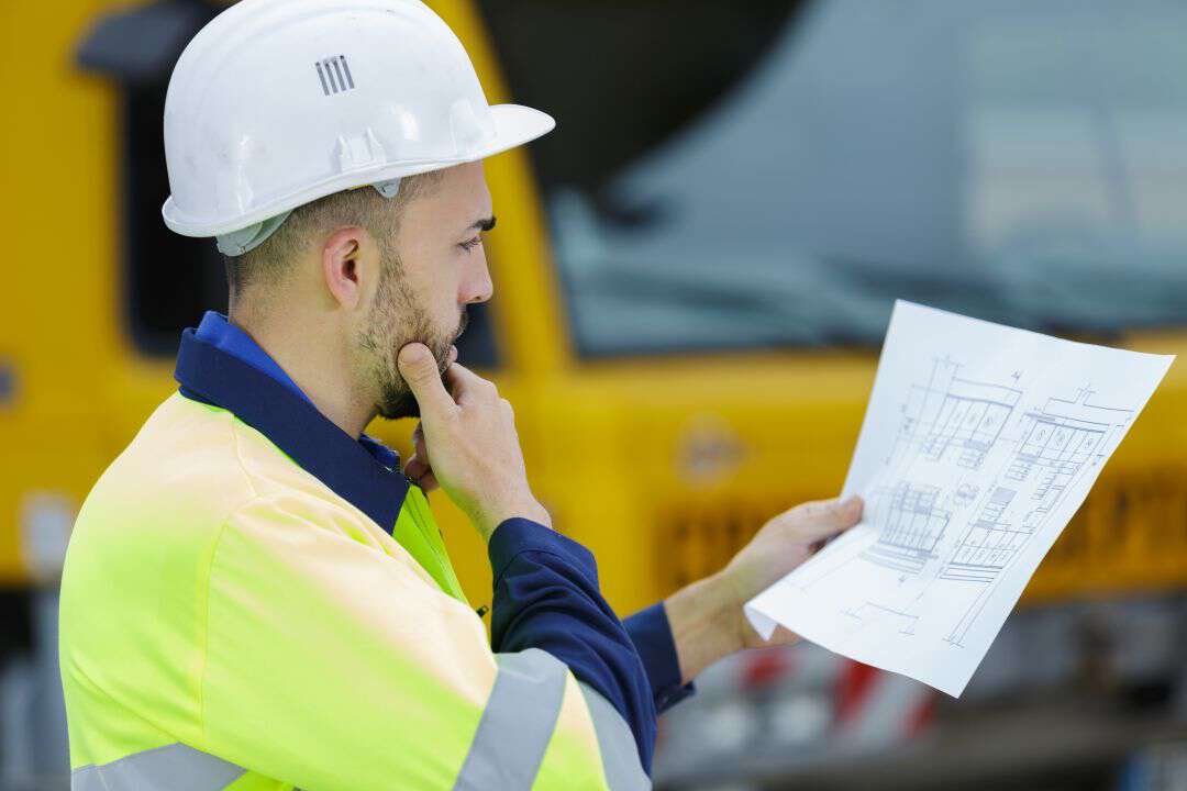 Bilde viser en mann som ser på byggtegninger