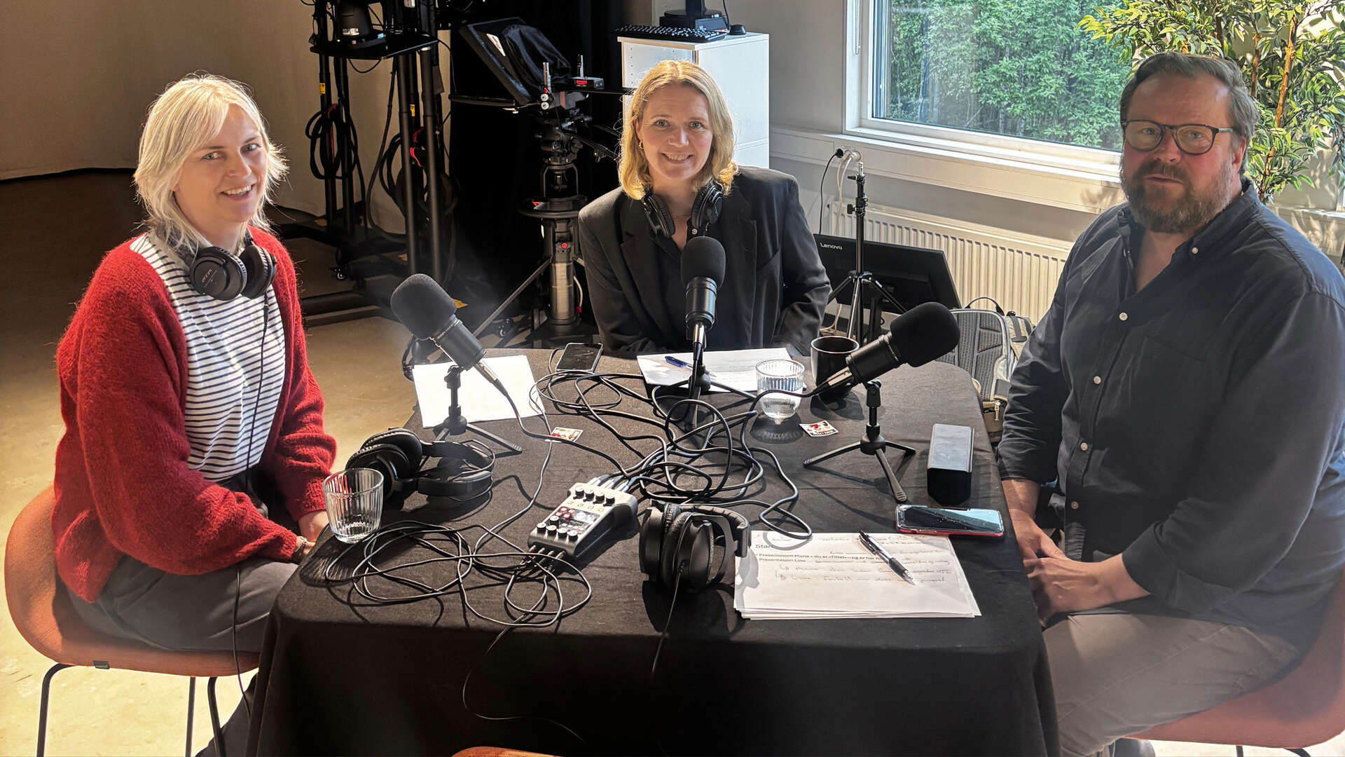 3 personer i studio rundt et bord med mikrofoner