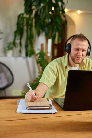 Nettstudent som ser inn i sin PC og noterer.
