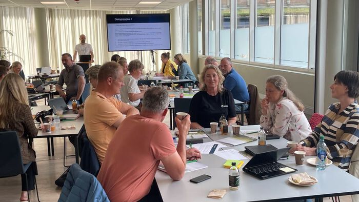Bilde av deltakere i workshop som sitter hved hver sine bord og arbeider. 