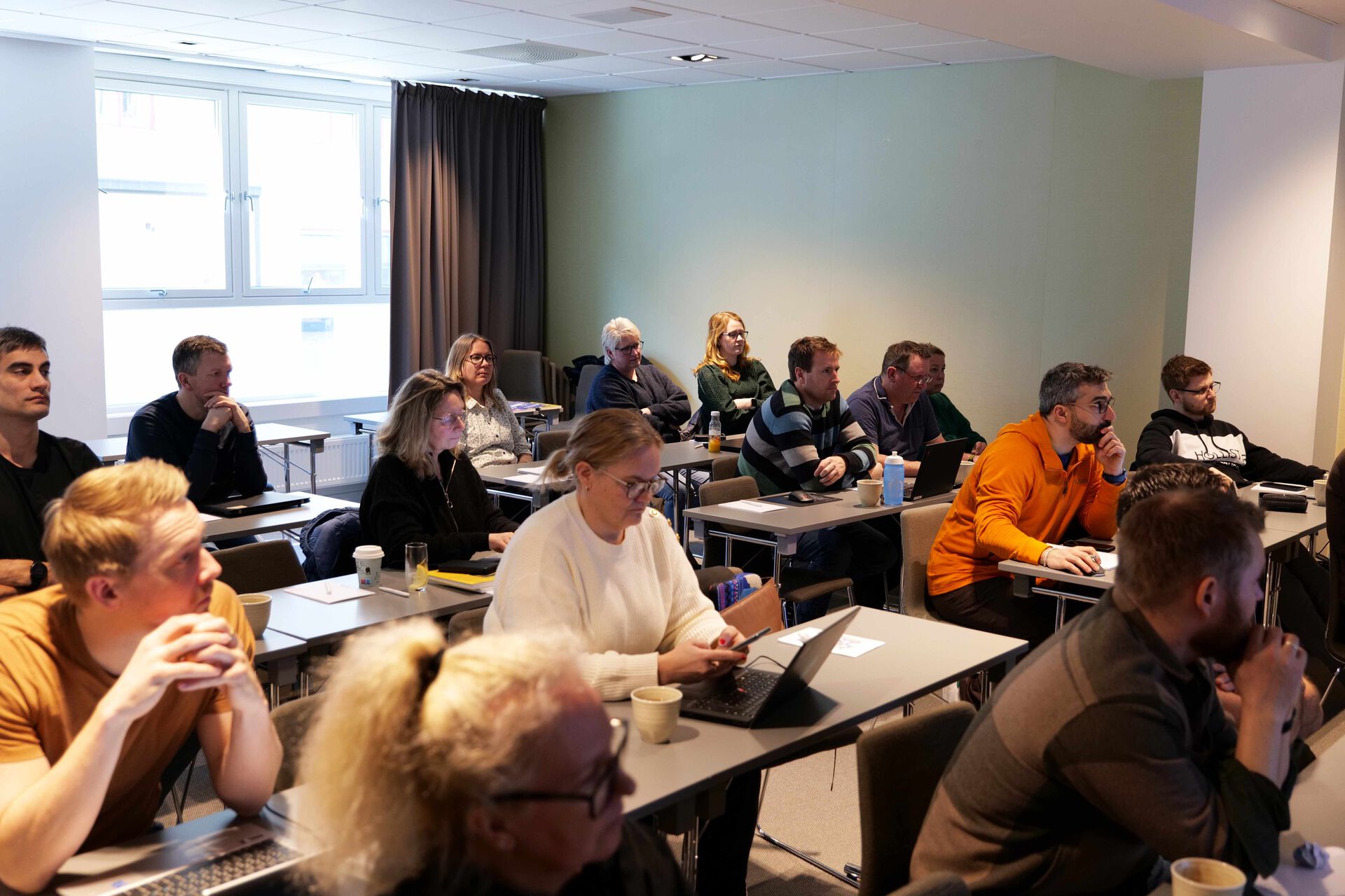 Studenter som sitter ved pulter i et klasserom.