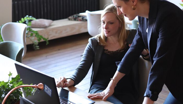 Bilde av 2 voksne studenter som ser på en PC