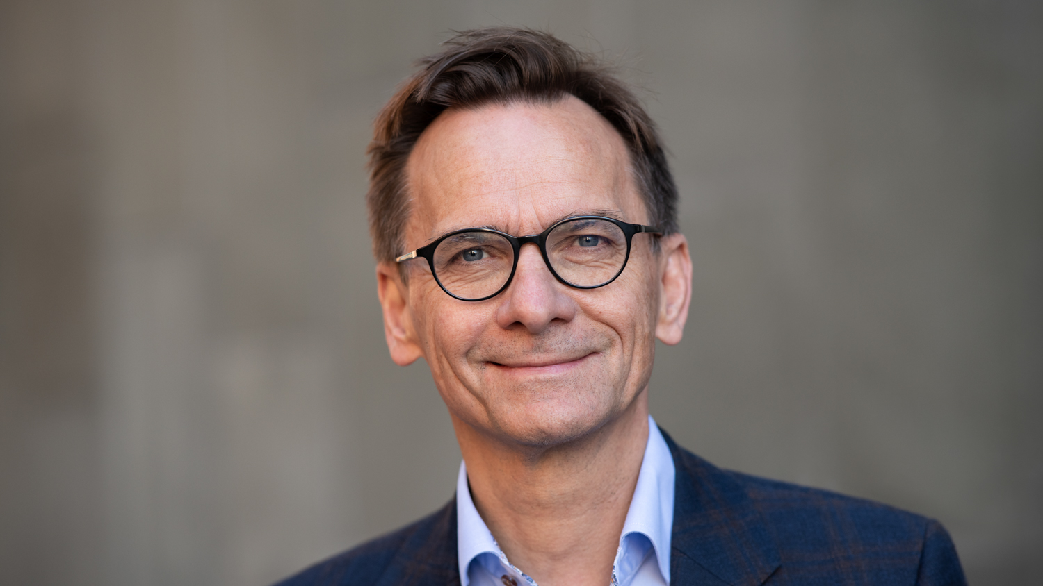 Portrettbidle av Christen Krogh, rektor OsloMet, med blå skjorte og jakke mot uskarp bakgrunn
