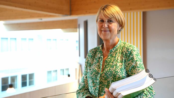 Anna Ottosen står og holder i tre permer.