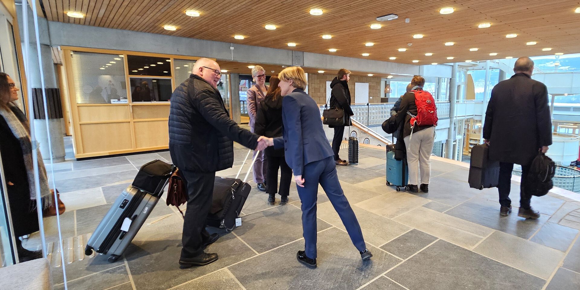 Anna L. Ottosen står med ryggen delvis til og hilser på Nokut-komiteen når de kommer til campus Lillehammer, med sekker og kofferter.