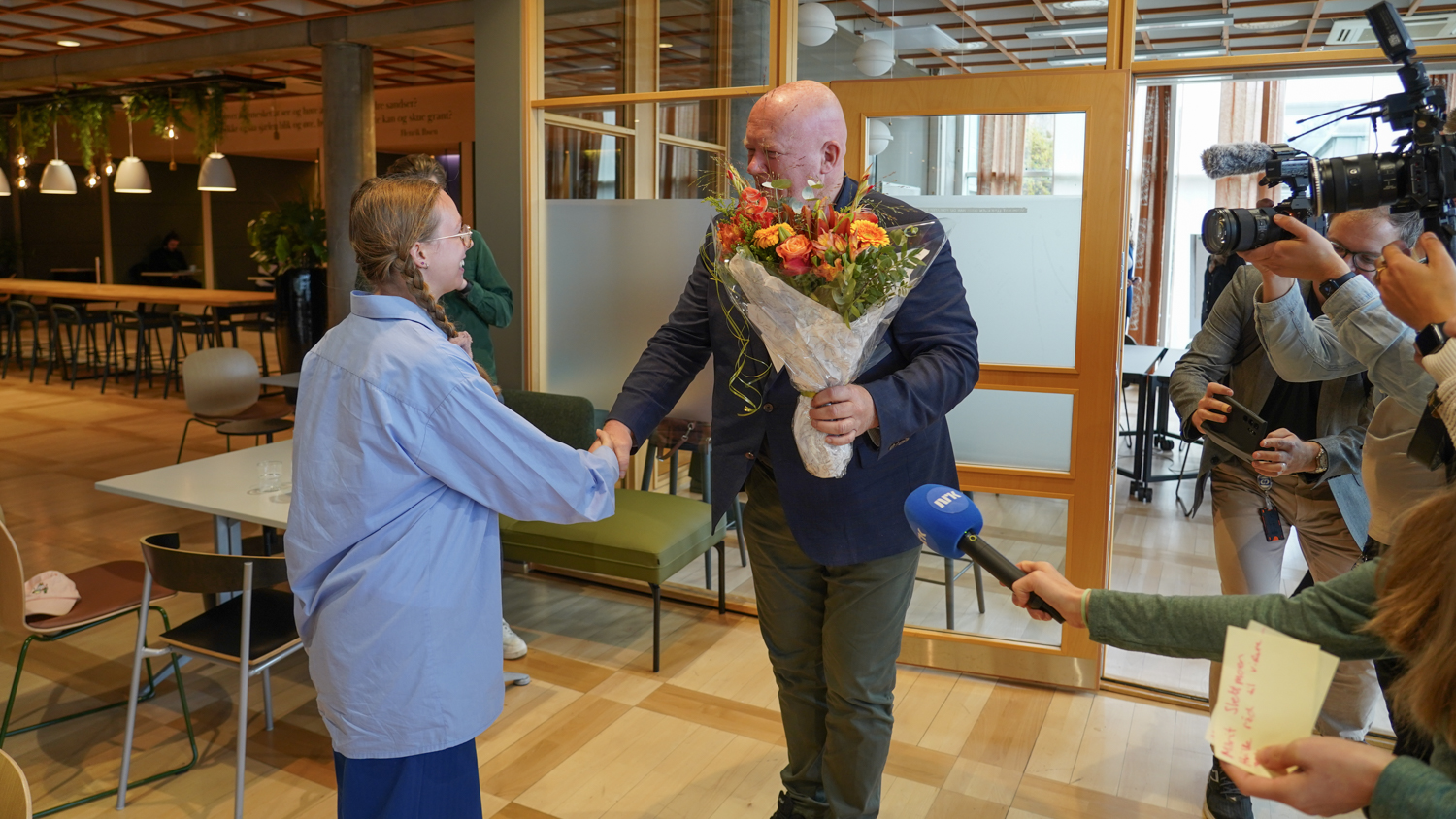Student overrekker blomster til Peer Jacob Svnekerud i kantina