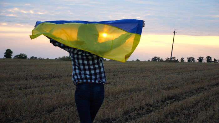Dame med ukrainsk flagg på er jordet