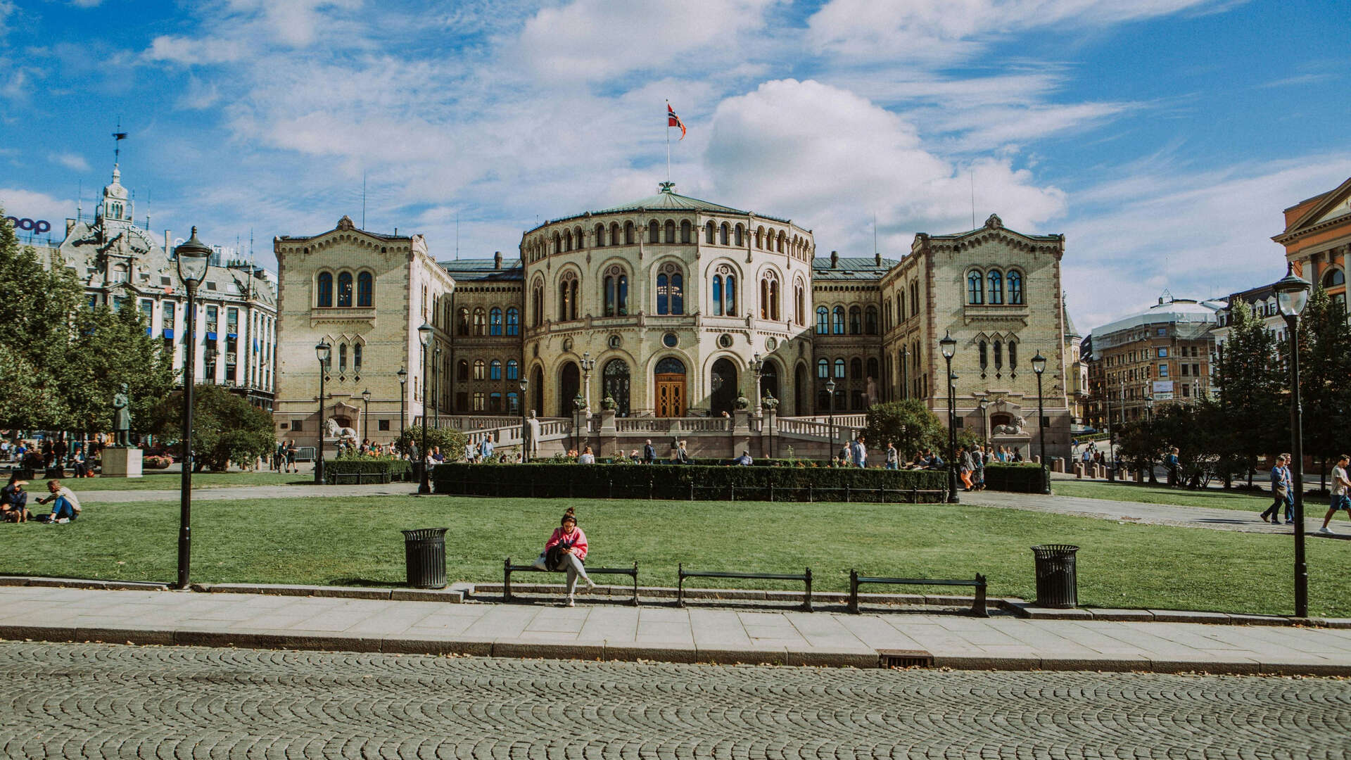 stortingsbygget med park foran og dame på en benk
