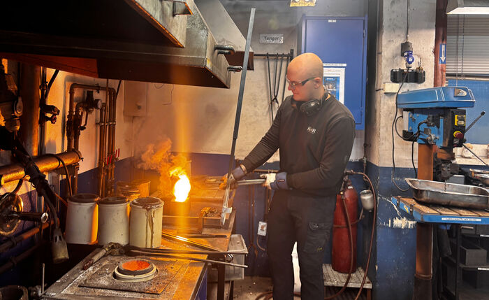 mann som smelter gull over en åpen flamme