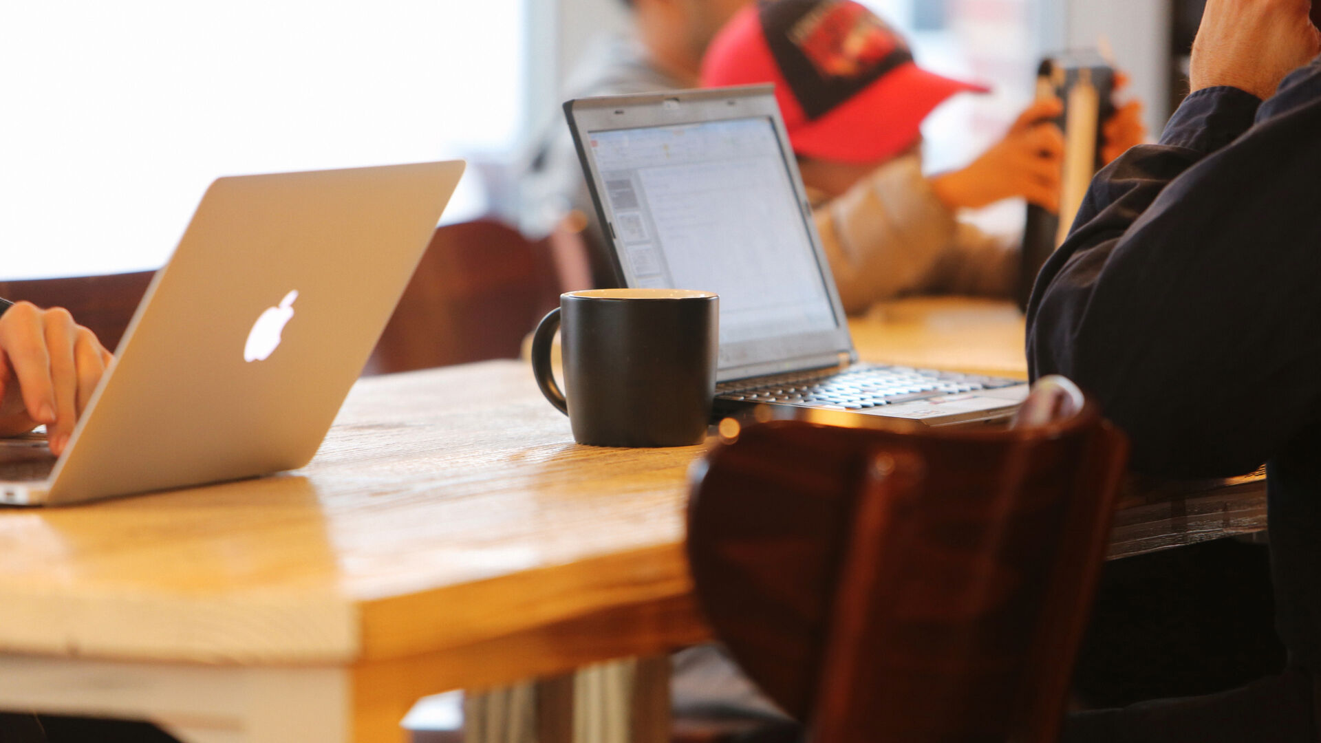 personer rundt et bord med pc og kaffekopp