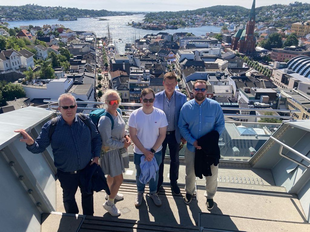 Fire personer på en høyde med Arendal sentrum og sjøen i bakgrunnen