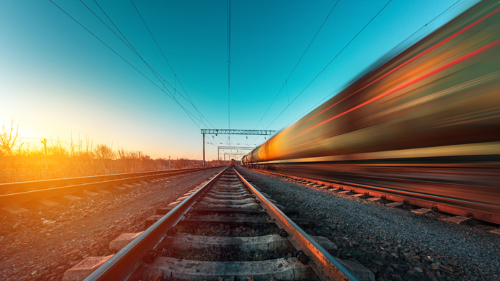Photo of train tracks, and train passing by on right side.