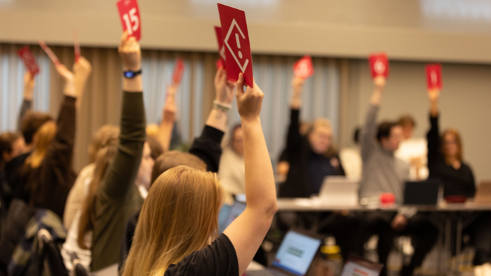 Student delegates raising pink voting cards in the air.