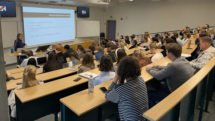 Studentrådet i Lillehammer samlet i et auditorium, og følger med på at studentrådslederen presenterer en sak