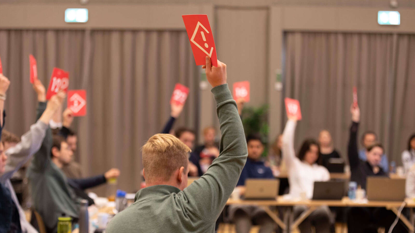 Et samlet studentting voterer over en sak ved å holde opp stemmeskilt
