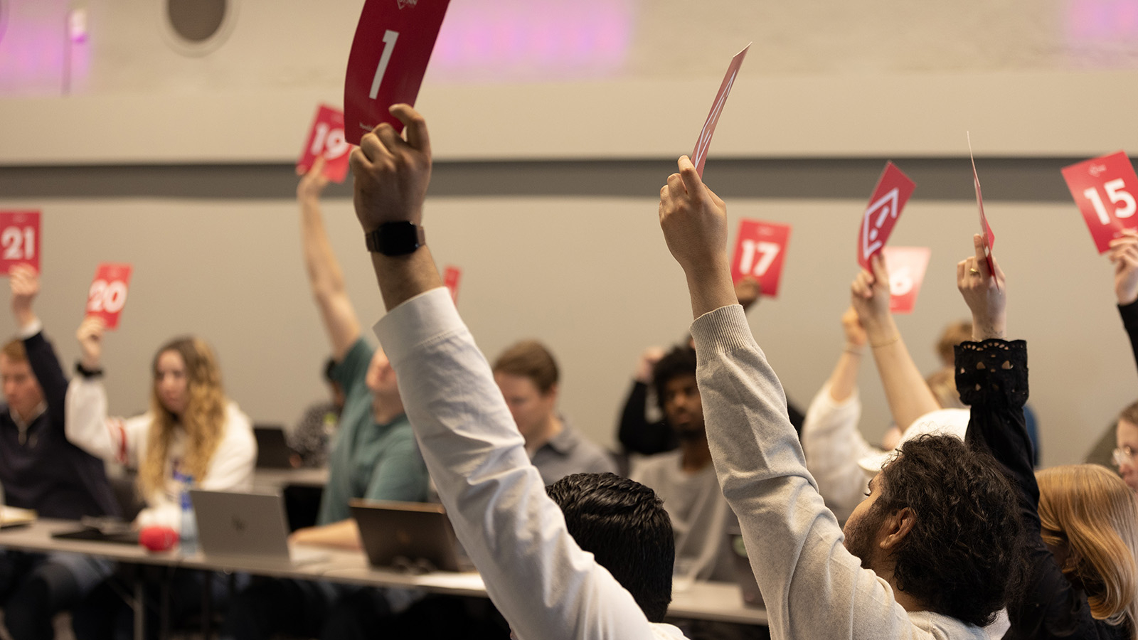 Et samlet studentting voterer over en sak ved å holde opp stemmeskilt