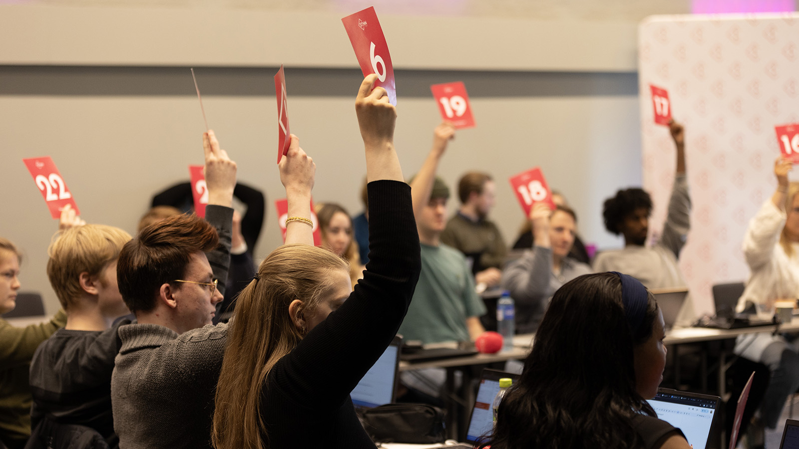 Picture of Student Parliament delegates voting with pink voting signs