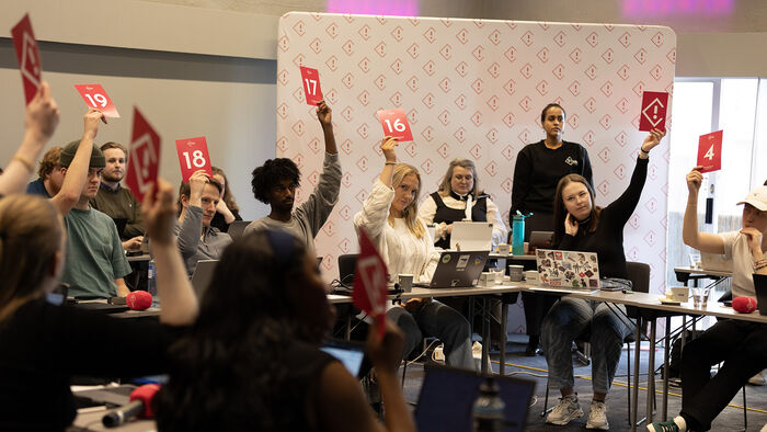Studentrepresentantene i Studenttinget voterer ved å løfte rosa stemmeskilt med hvite detaljer