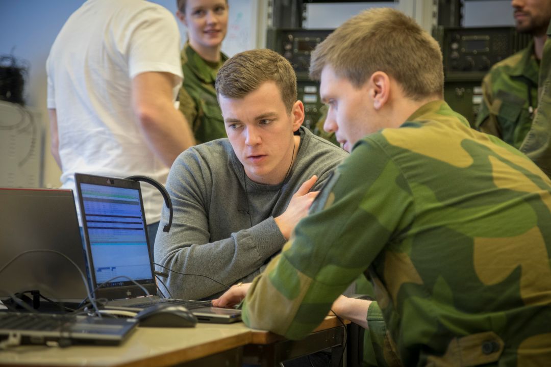 Soldater som sitter sammen og ser på en pc-skjerm.