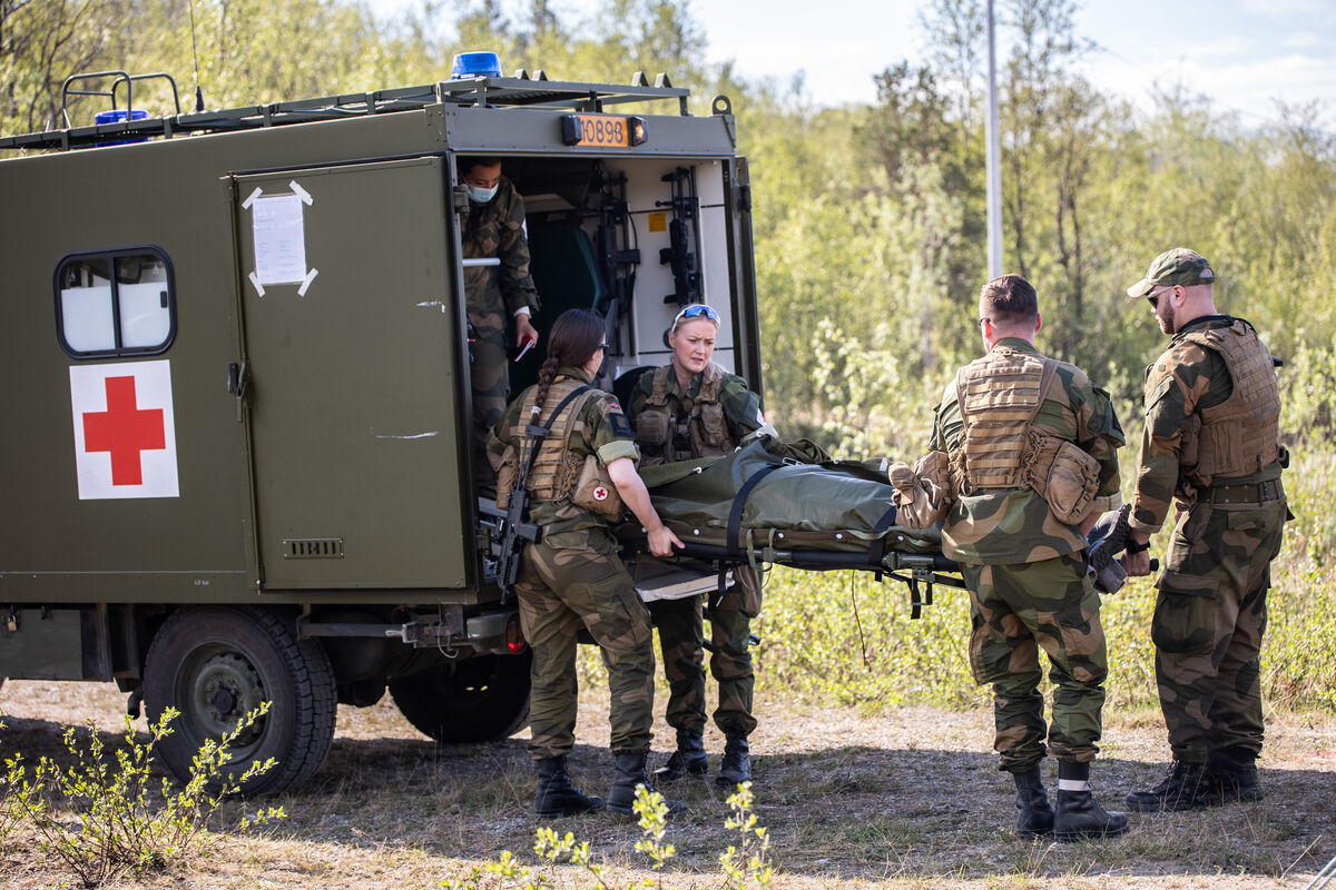 Sanitetspersonell bærer inn en skadet soldat inn i militærkjøretøy